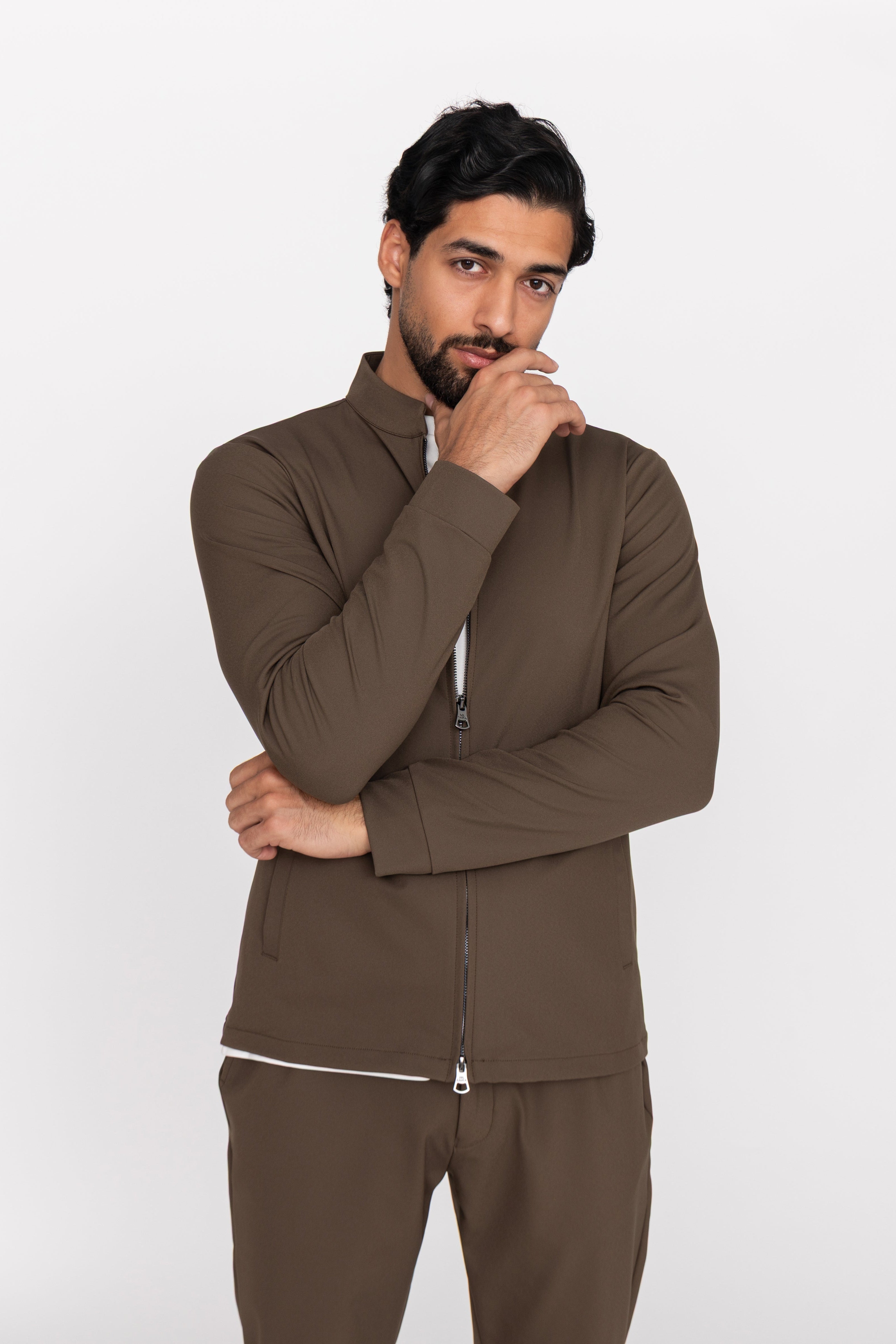 Man wearing a brown tracksuit against a white background